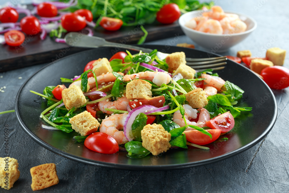 Fresh Healthy Prawns salad with tomatoes, red onion on black plate. concept healthy food