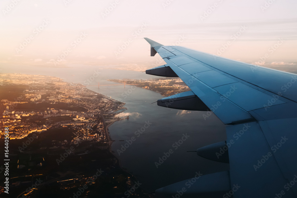 Airplane wing view from window seat above Vasco de Gama bridge i