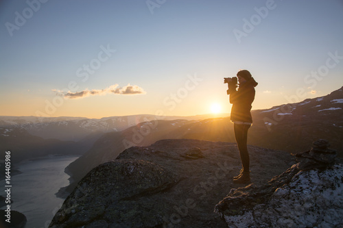 Young woman photographing the sunrise in Norway © Oliver