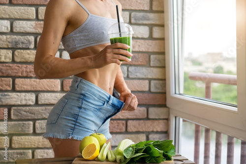 Fit woman drinking vegetable Green detox smoothie.  raw food diet photo