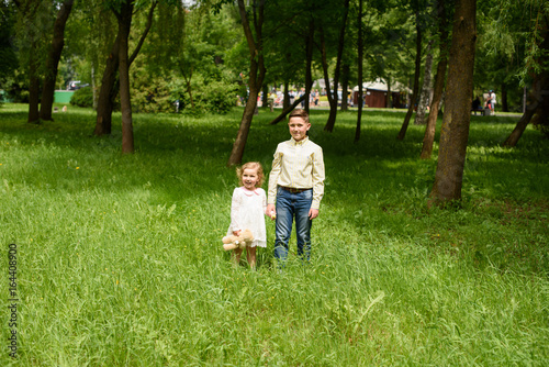 Little children brother with sister spend time together in the park in the summer