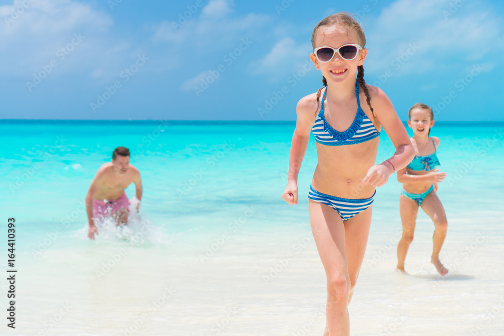 Little girls and happy dad having fun on the seashore. Close-up the youngest daughter running on the beach Little girls and happy dad having fun on the seashore. Close-up the youngest daughter running on the beach