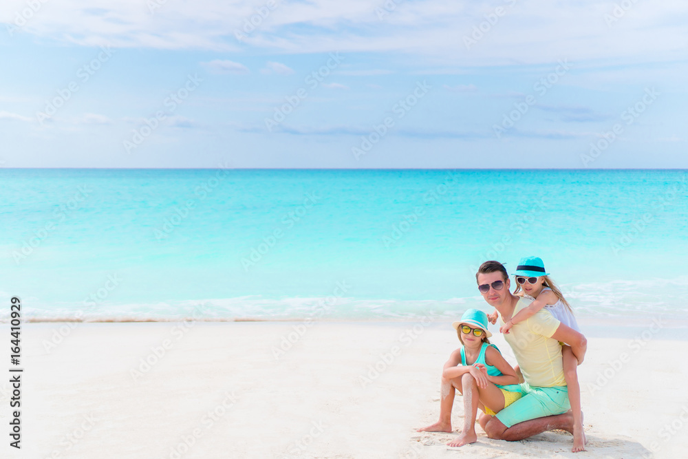 Family on white tropical beach on caribbean island. Father and little daughters on the seashore