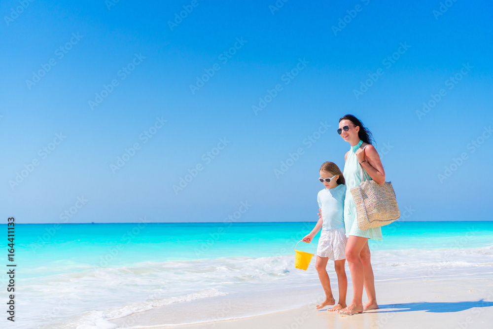 Family of mom and kid walking on white beach