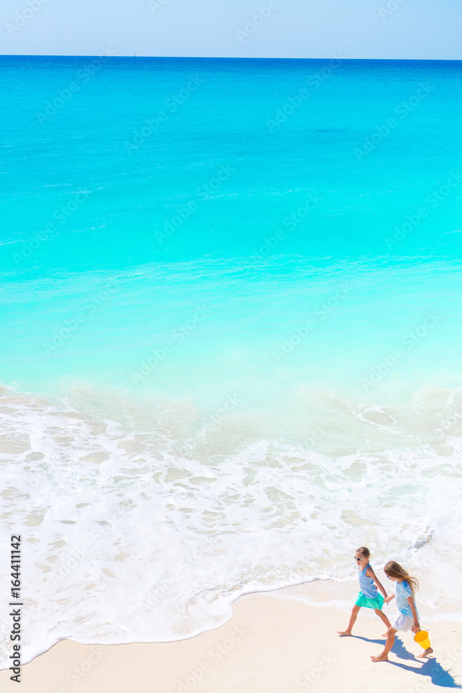 Adorable little girls on the beach. Top view of kids walking on the seashore Adorable little girls on the beach. Top view of kids walking on the seashore