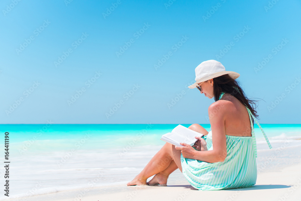Young woman reading book on white sand beach Young woman reading book on white sand beach
