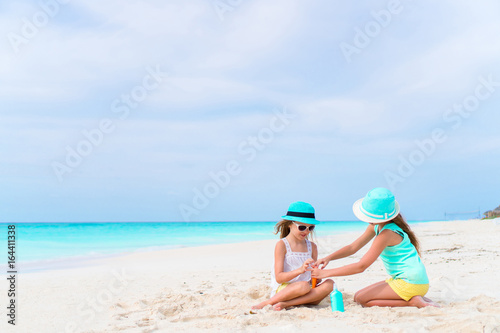 Two caring girls take care of each other on white beach. The concept of protection from ultraviolet radiation