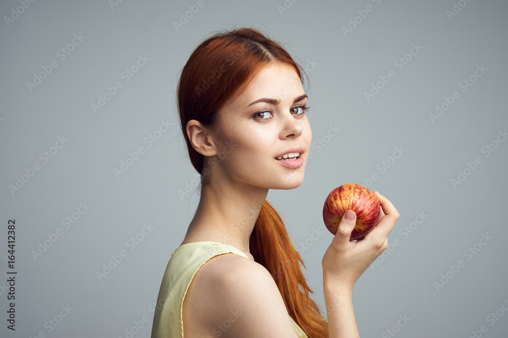Beautiful young woman on a gray background holding an apple Beautiful young woman on a gray background holding an apple