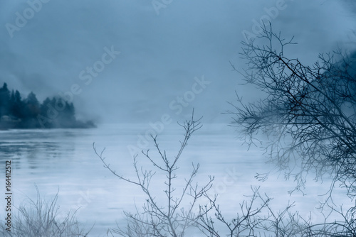 Fototapeta Naklejka Na Ścianę i Meble -  Rain and mist on ice covered northern lake in winter