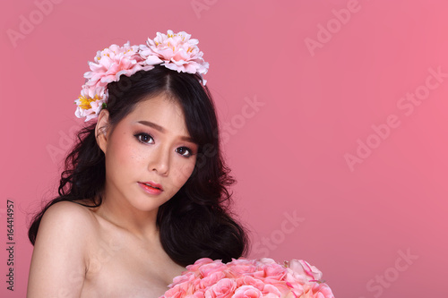 Beautiful Asian Woman black hair with flora crowd, holding bouquet artificial rose over chest photo