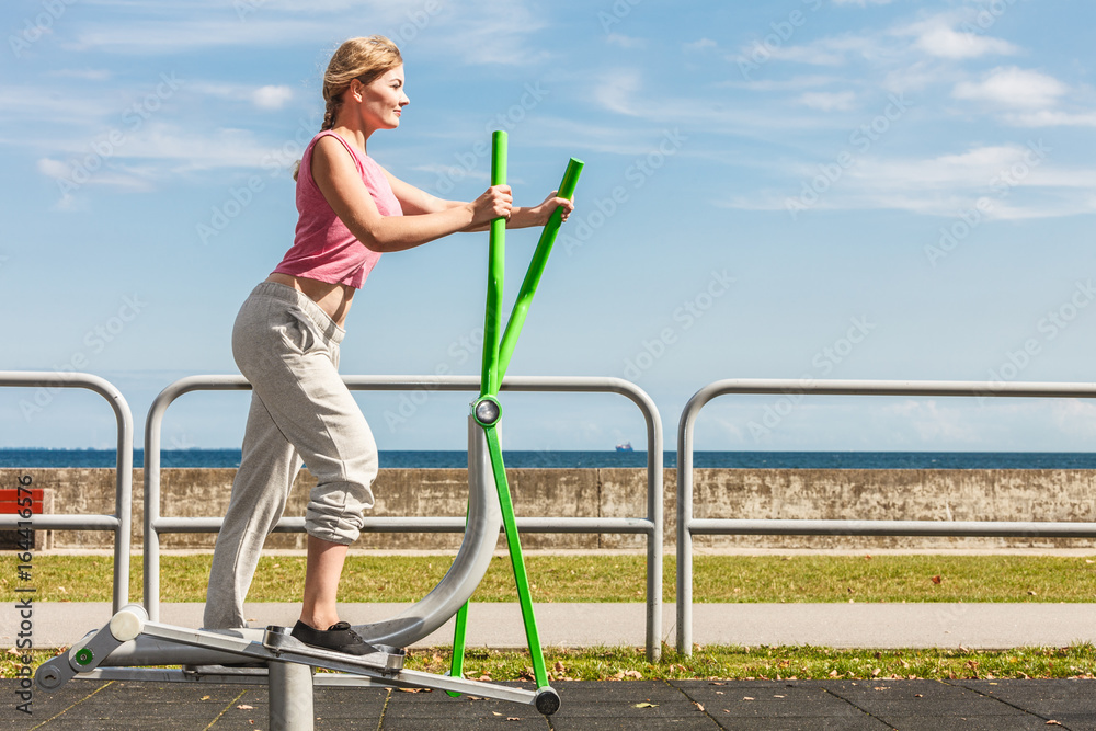 Active woman exercising on elliptical trainer.