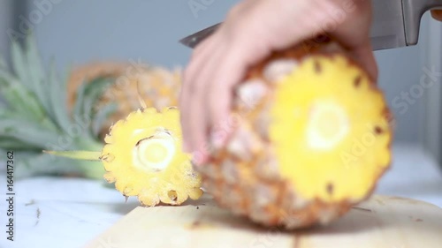 Close up shot hands of women using kitchen knife to cutting and peeling ripe pineapple shallow depth of field  photo