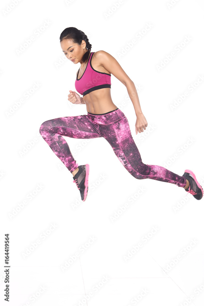 Tan Skin Asian Fitness Girl in Sport Bra black spandex pants Exercise warm  up in white studio room, practice pose high jump push forward Stock Photo