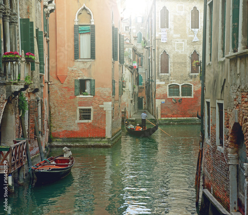 Venetian gondolier punting gondola through green canal waters of Venice Italy © aimy27feb