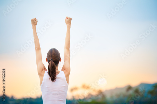 People winning achievement concept. Young woman with fist in the air celebrating success and happiness. 