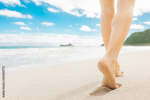 Beach holiday background. Closeup of woman walking down a white sand beach in Hawaii.