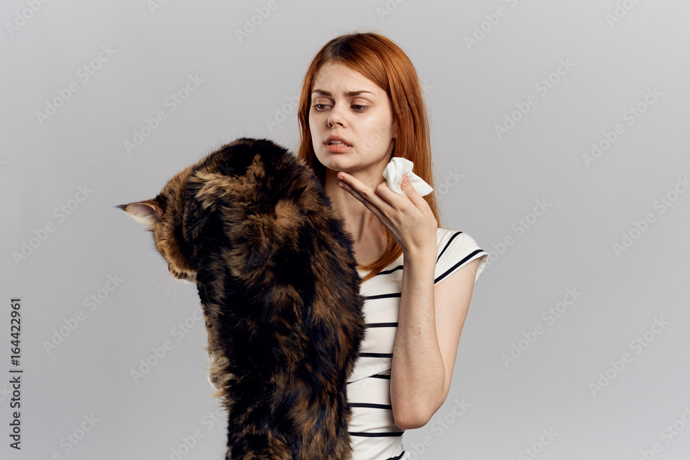 Beautiful young woman on white isolated background holds a cat, an allergy