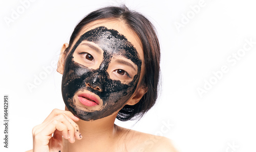 Beautiful young woman on white isolated background in black coal face mask, asian