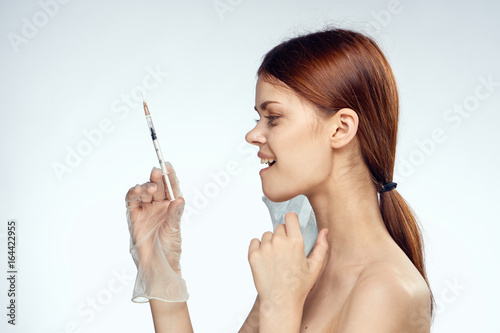 Beautiful young woman on white isolated background holds a syringe, medicine, plastic