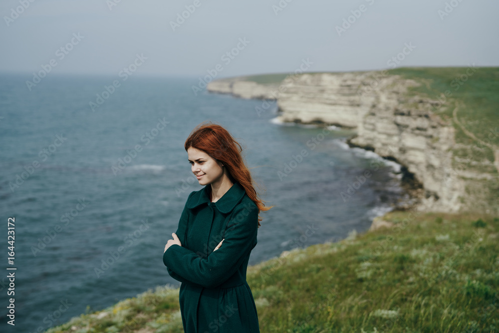 Beautiful young woman on a cliff of a mountain near the sea