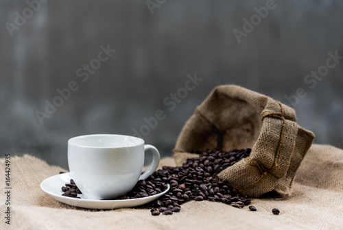 Empty coffee cup and coffee beans on the sackcloth has ready fill up coffee to the coffee cup.