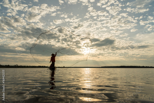 Silhouette of Fishermen throwing net fishing in sunset time at Wanon Niwat district Sakon Nakhon Northeast Thailand. photo