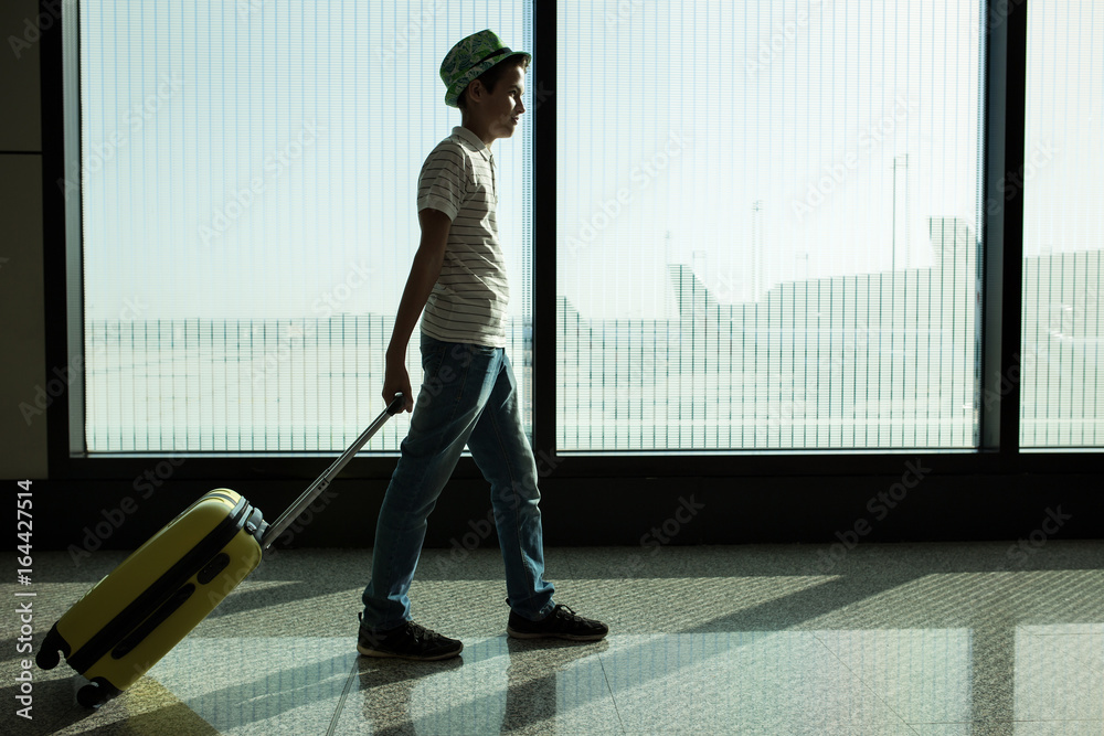Fototapeta premium little boy with suitcase waiting in the airport