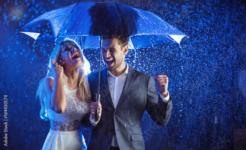Cheerful couple enjoying the summer rain