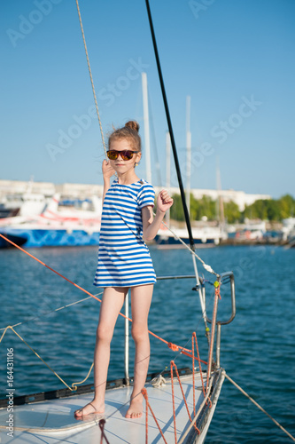 beautiful slender little girl in a striped t-shirt and sunglasses aboard luxury boat