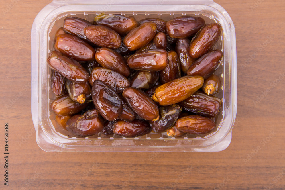 Dried date fruits in plastic container on wooden table. Top view Dried date fruits in plastic container on wooden table. Top view