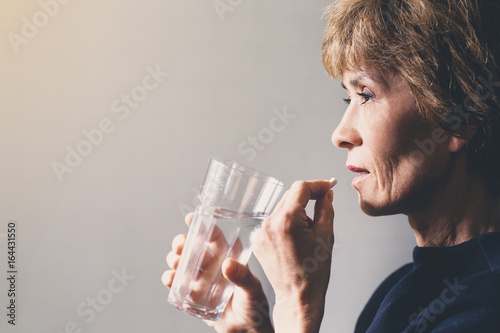 Adult woman with a pill and a glass of water / health care concept