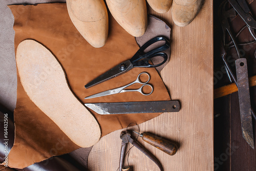 Cobbler tools in workshop on the wooden table . Top view. photo