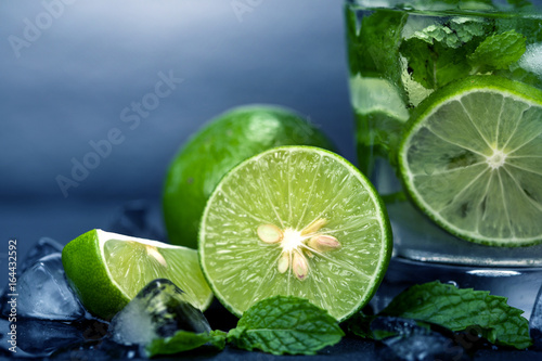 Close up the fresh mojito cocktail with fresh lime and mint leaf on black stone background