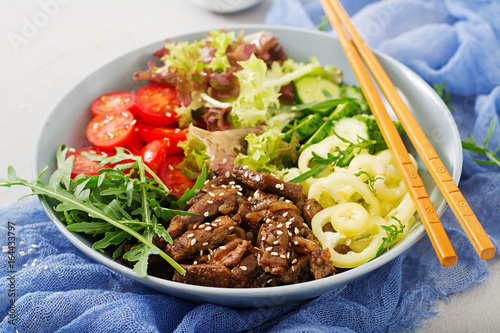 Salad with beef teriyaki and fresh vegetables - tomatoes, cucumbers, paprika, arugula and lettuce in bowl.
