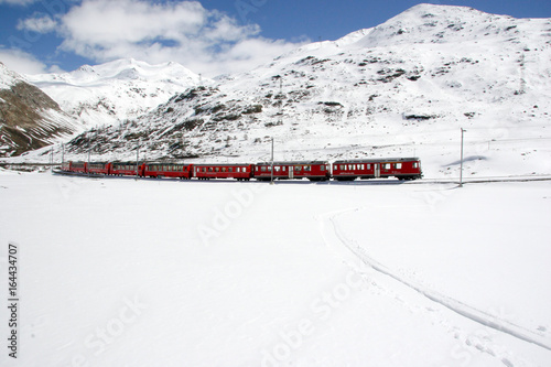 red train traveling through winter landscape in the Swiss Alps near St. Moritz