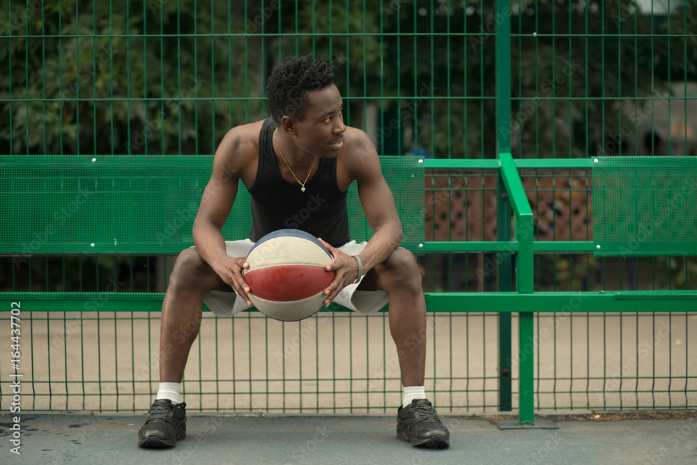 Portrait of african american man sitting on basketball court
