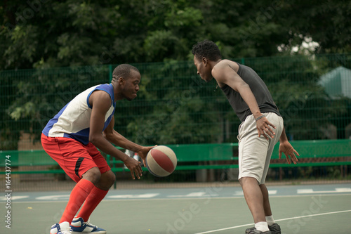 African american man friends playing on basketball court. Real authentic activity.