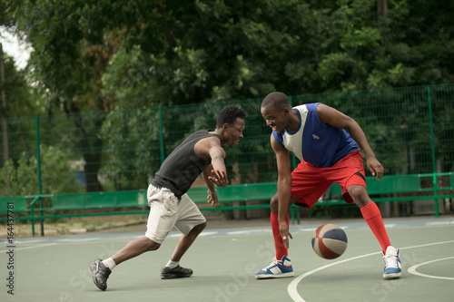 African american man friends playing on basketball court. Real authentic activity.