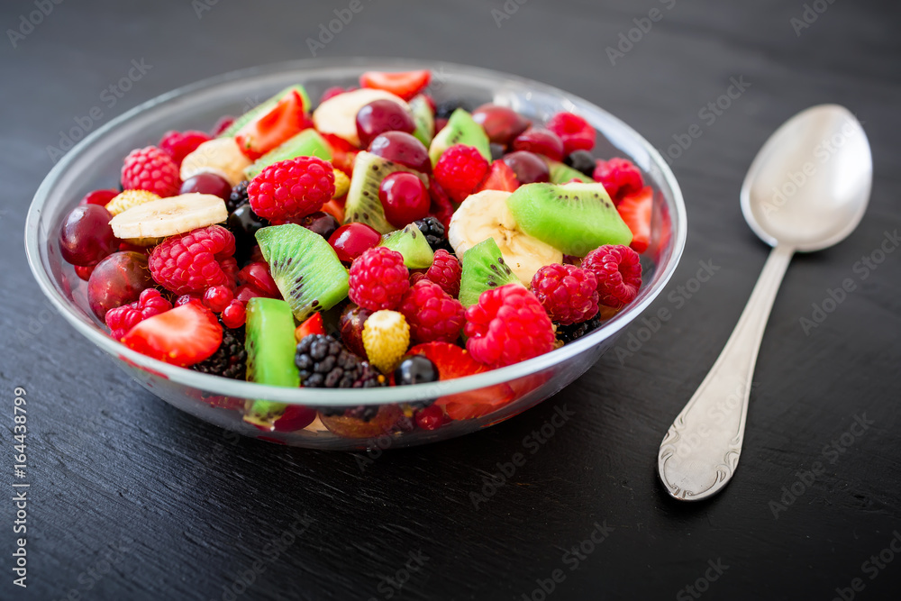 Fruit salad in glass plate on dark background. Natural breakfast Fruit salad in glass plate on dark background. Natural breakfast