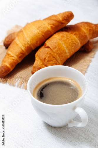 Croissants with coffee on a white table.