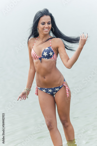 Young beautiful black-haired woman posing on the beach in the water