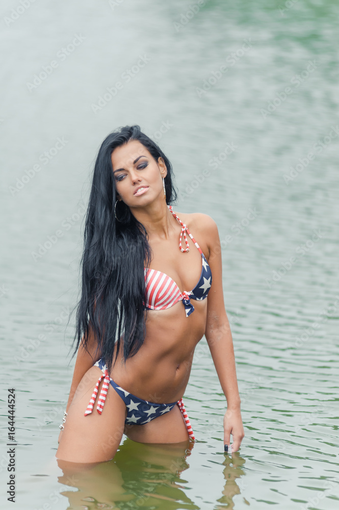 Young beautiful black-haired woman posing on the beach in the water