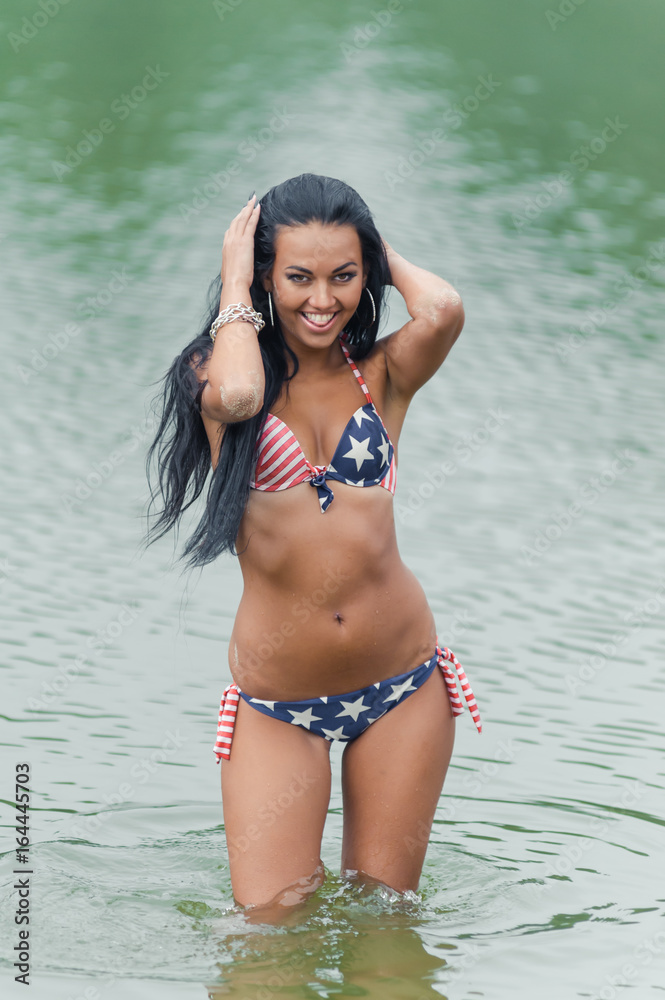Young beautiful black-haired woman posing on the beach in the water