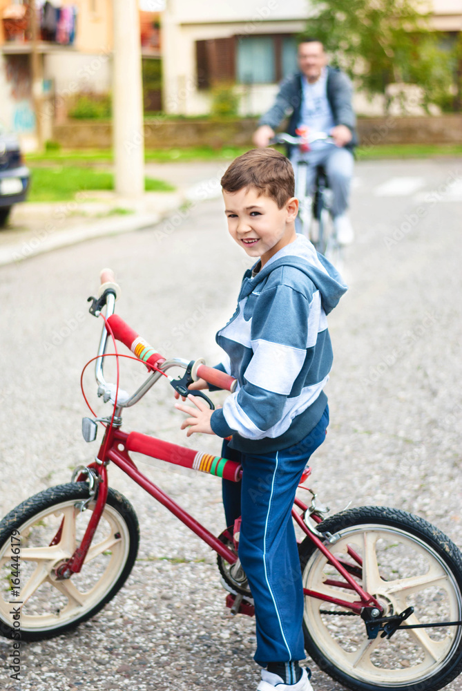 Boy rides bike with his dad on the street