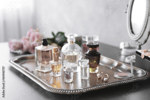 Metal tray with bottles of perfume on table