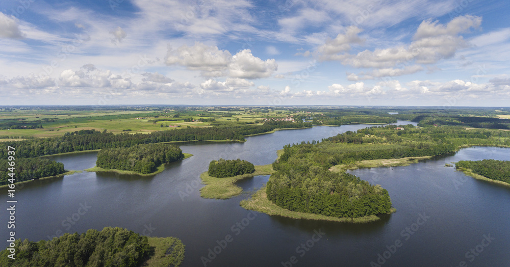 Fototapeta Aerial view of green islands and clouds at summer sunny day.Wydminy lake on Masuria in Poland.