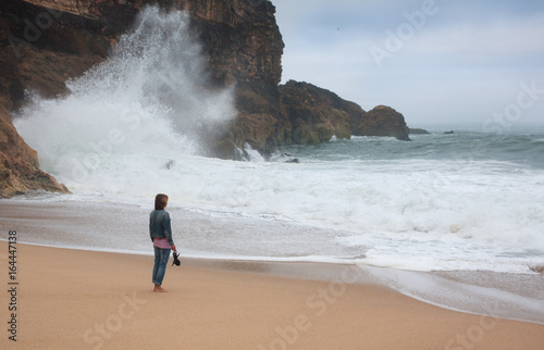Young woman walking alone on the deserted coast of the Atlantic Ocean, Portugal