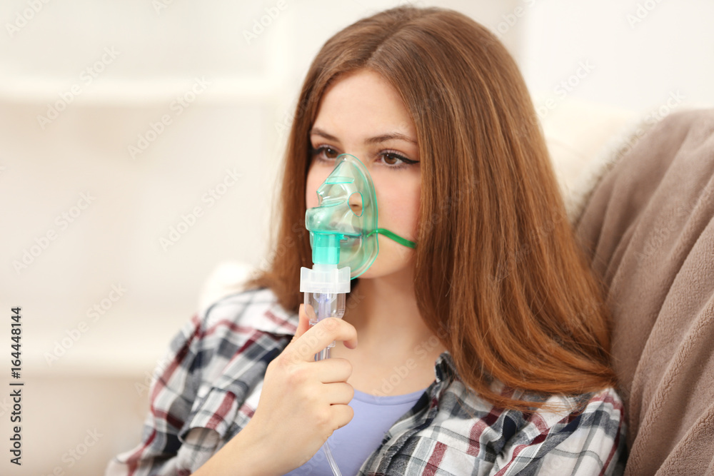 Young woman using nebulizer for asthma and respiratory diseases at home