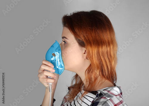 Young woman using nebulizer...