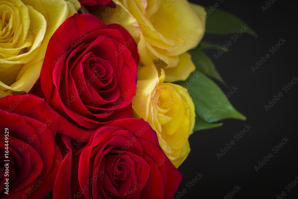 Part of a bouquet of red and yellow roses in a basket close-up.